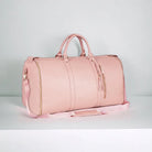 Pink leather weekender bag with dual handles and detachable shoulder strap, featuring gold zippers and tassel accents. Perfect for travel and style.