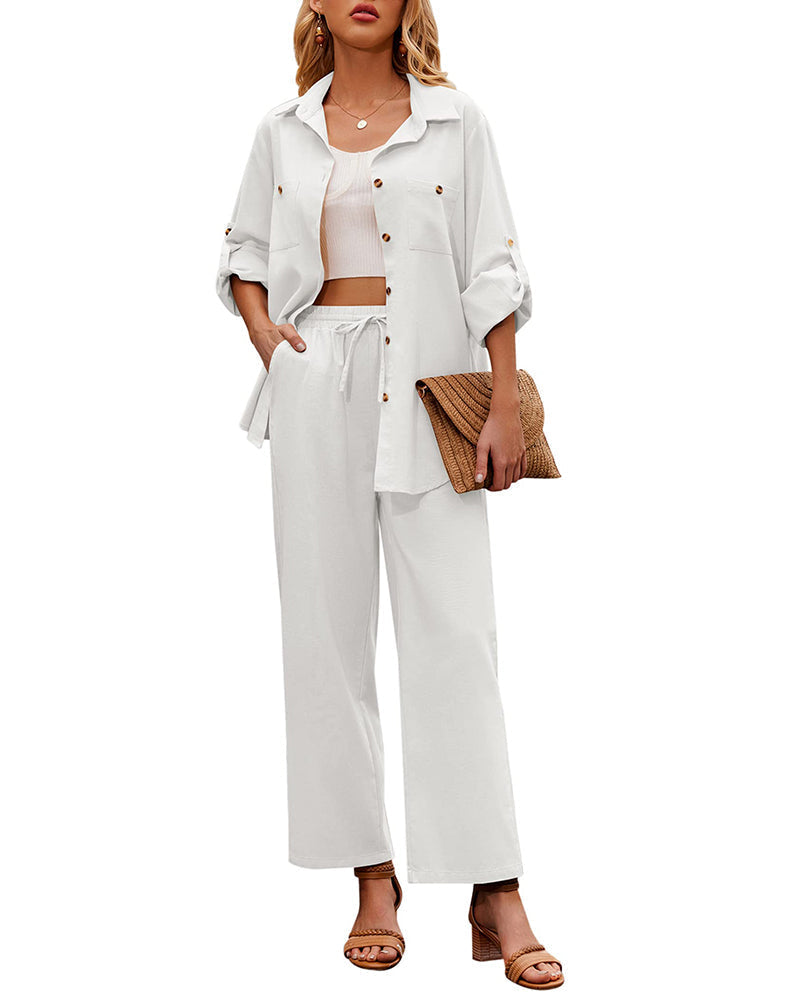 Woman in stylish white two-piece outfit with button-up shirt and wide-leg pants, holding a woven clutch. Fashionable summer look with sandals.