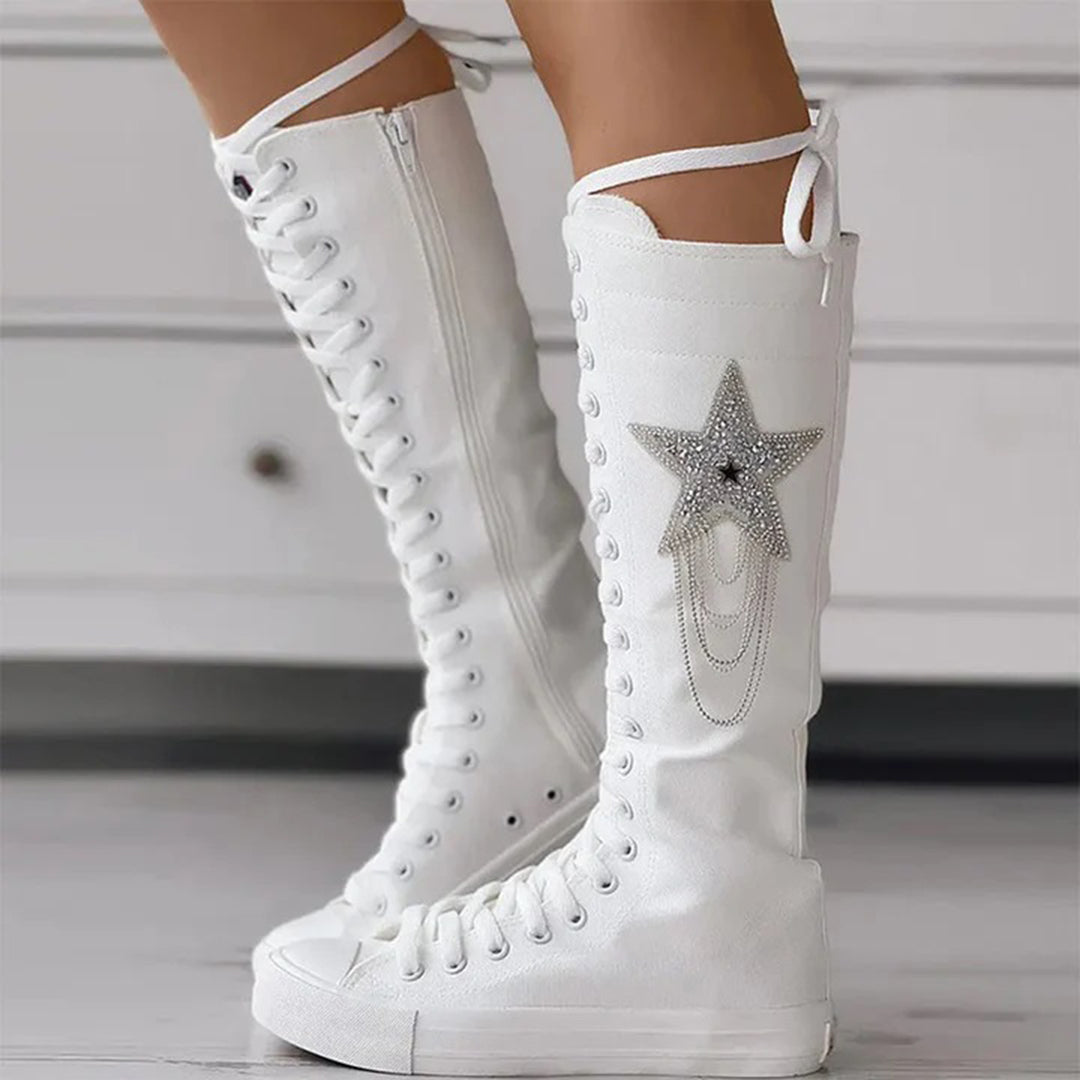 White knee-high lace-up boots with star embellishment and chain details, stylish women's footwear, trendy fashion accessory, side zipper closure.