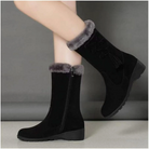 Women's black winter boots with faux fur lining, mid-calf height, side zipper, and platform sole. Stylish, warm footwear for cold weather.