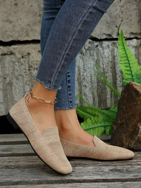 Women's beige woven loafers paired with skinny jeans, displayed outdoors on wooden planks. Fashionable casual footwear, perfect for everyday style.