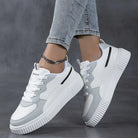 White and gray women's fashion sneakers with thick soles, worn with light blue jeans. Stylish casual footwear for trendy streetwear outfits.