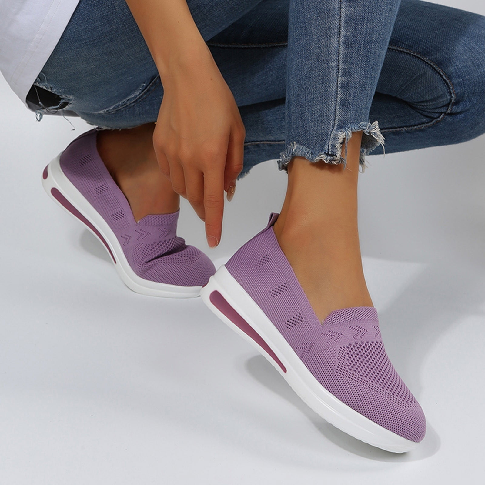 Woman wearing purple slip-on sneakers with white soles, sitting in ripped jeans. Comfortable, stylish footwear for casual wear. Fashionable shoes.