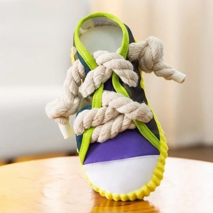 Colorful baby shoe with thick rope laces, featuring a vibrant design with purple, green, and yellow accents, placed on a wooden surface.