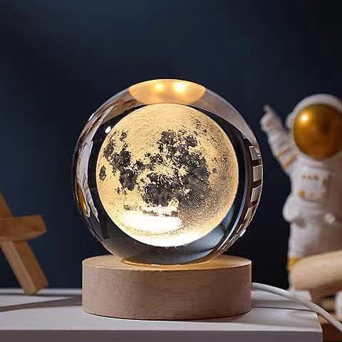 Moon lamp on wooden base with astronaut figurine, glowing in dark room. Perfect for space-themed decor, night light, or unique gift idea.