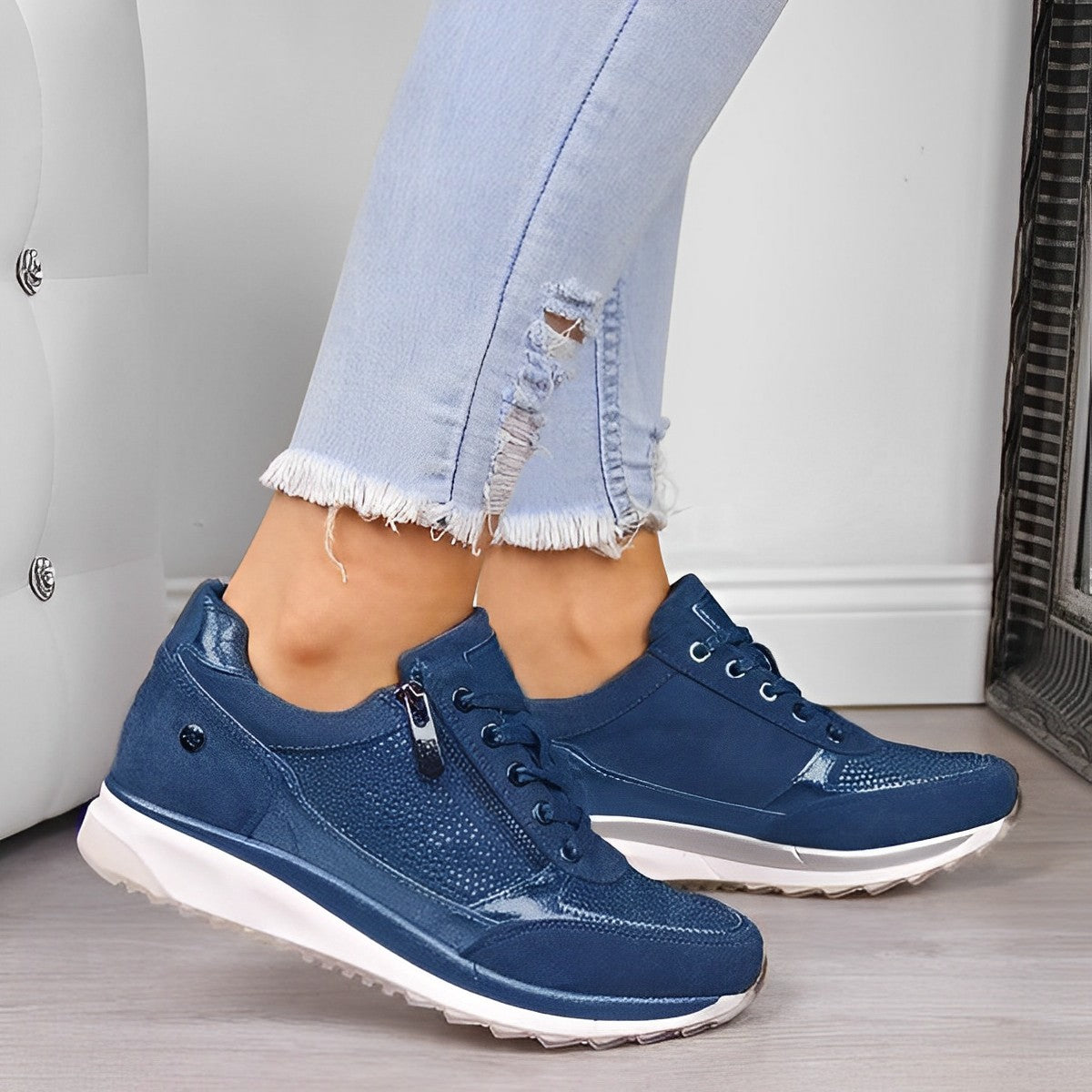 Women's blue casual sneakers with textured design, white soles, and lace-up closure, paired with light blue ripped jeans. Fashionable footwear.