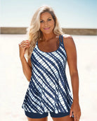 Woman in blue and white striped tankini swimsuit on beach, smiling. Summer swimwear fashion, beachwear style, ocean background.