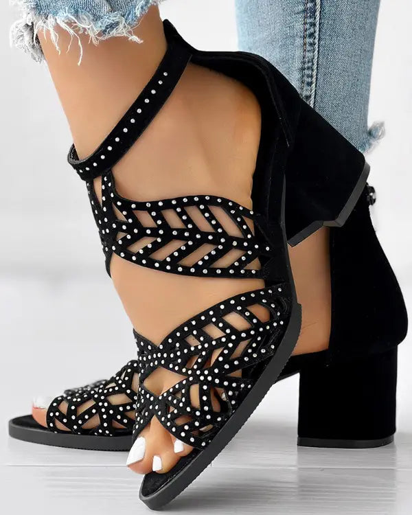 Black strappy high heel sandals with rhinestone embellishments, worn with distressed denim jeans. Fashionable women's footwear, stylish summer shoes.