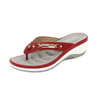 Red women's wedge sandal with cushioned sole, perforated insole, and decorative metal accent. Comfortable summer footwear, stylish flip-flop design.