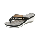 Black and white wedge flip-flop sandal with perforated insole, metallic embellishment, and comfortable design. Perfect for casual summer wear.