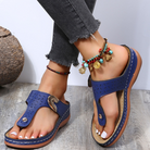 Blue orthopedic sandals with arch support on a woman's feet, paired with beaded anklets. Comfortable summer footwear, casual style, fashion accessory.