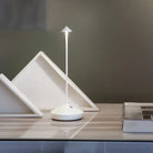 Modern minimalist LED desk lamp with sleek design, featuring a triangular base and slim stem, ideal for contemporary home or office decor.