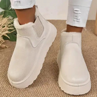 Women's white faux fur ankle boots with elastic side panels and thick soles, styled with ripped white jeans. Cozy winter footwear fashion.