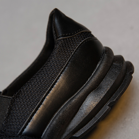 Close-up of a black athletic sneaker heel with mesh and leather details, showcasing modern design and comfort. Perfect for sports and casual wear.