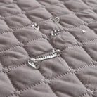 Quilted gray waterproof sofa protector with water droplets, showcasing spill-resistant fabric. Ideal for pet owners and families. Durable couch cover.