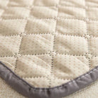 Quilted beige sofa protector with dotted pattern and gray border, designed for furniture protection. Durable, stylish couch cover for home decor.