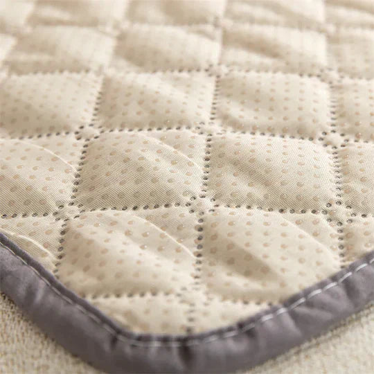 Quilted beige sofa protector with dotted pattern and gray border, designed for furniture protection. Durable, stylish couch cover for home decor.