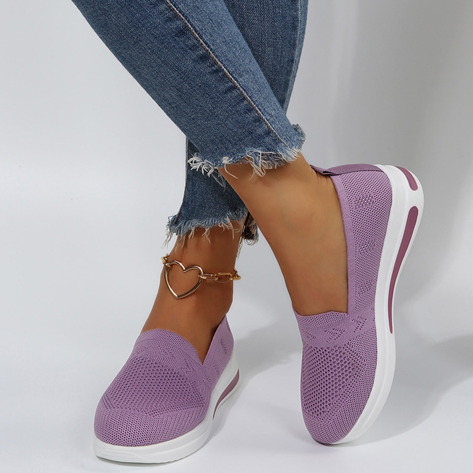 Women's purple slip-on sneakers with white soles, featuring breathable mesh design. Casual footwear paired with frayed hem jeans and heart anklet.