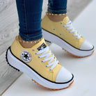 Yellow platform sneakers with white laces and black trim, featuring a star logo. Stylish casual footwear for women, perfect for fashion-forward looks.