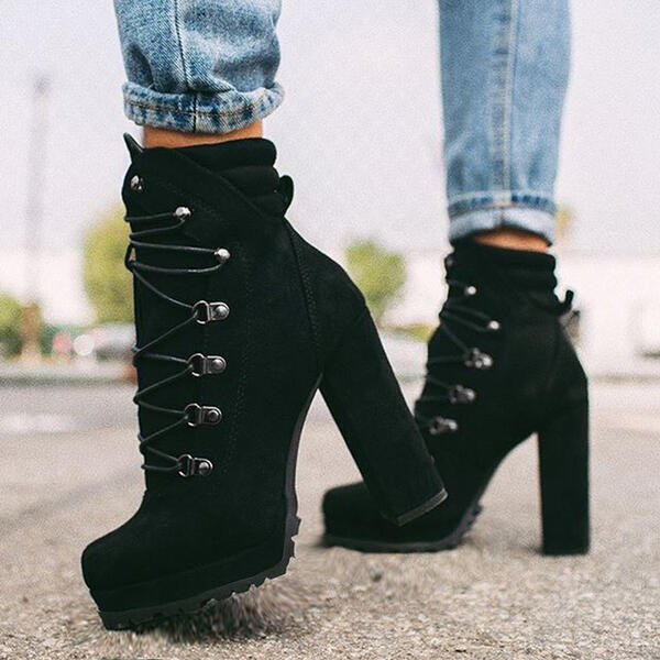 Black suede high-heeled ankle boots with lace-up design and rugged soles, worn with blue jeans, stylish women's footwear, outdoor fashion.