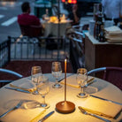 Outdoor restaurant table setting with elegant glassware, cutlery, and a candle centerpiece, creating a cozy dining ambiance on a city street.