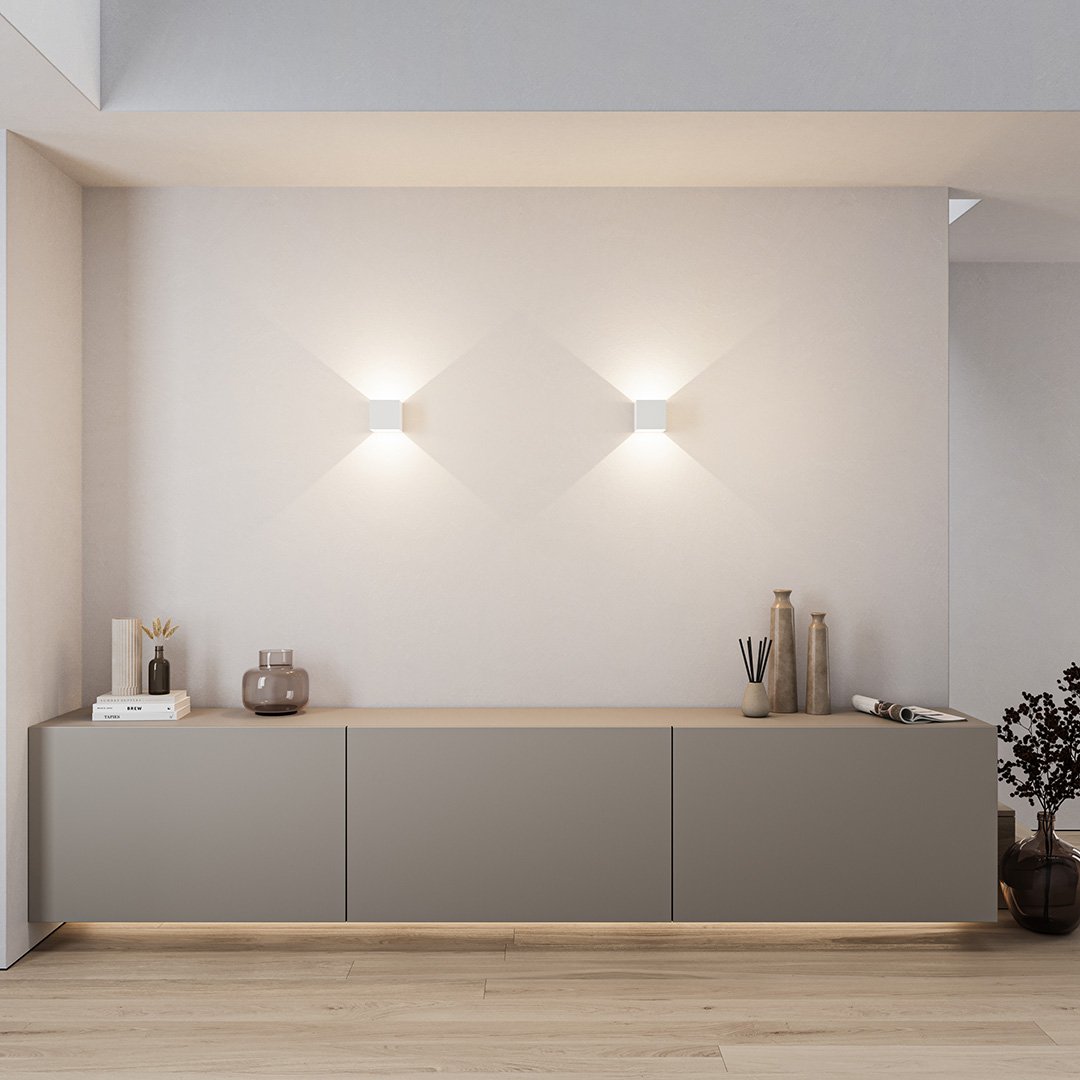 Modern minimalist living room with sleek gray sideboard, ambient wall lighting, decorative vases, and wooden flooring. Contemporary interior design.