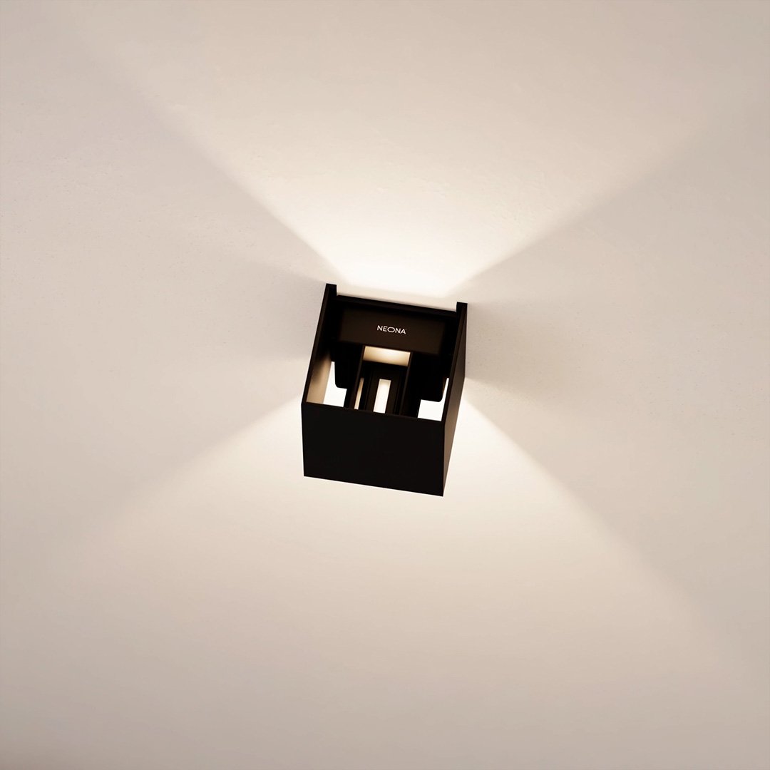 Modern black ceiling light fixture with geometric design, casting soft ambient light on white ceiling. Ideal for contemporary home lighting solutions.