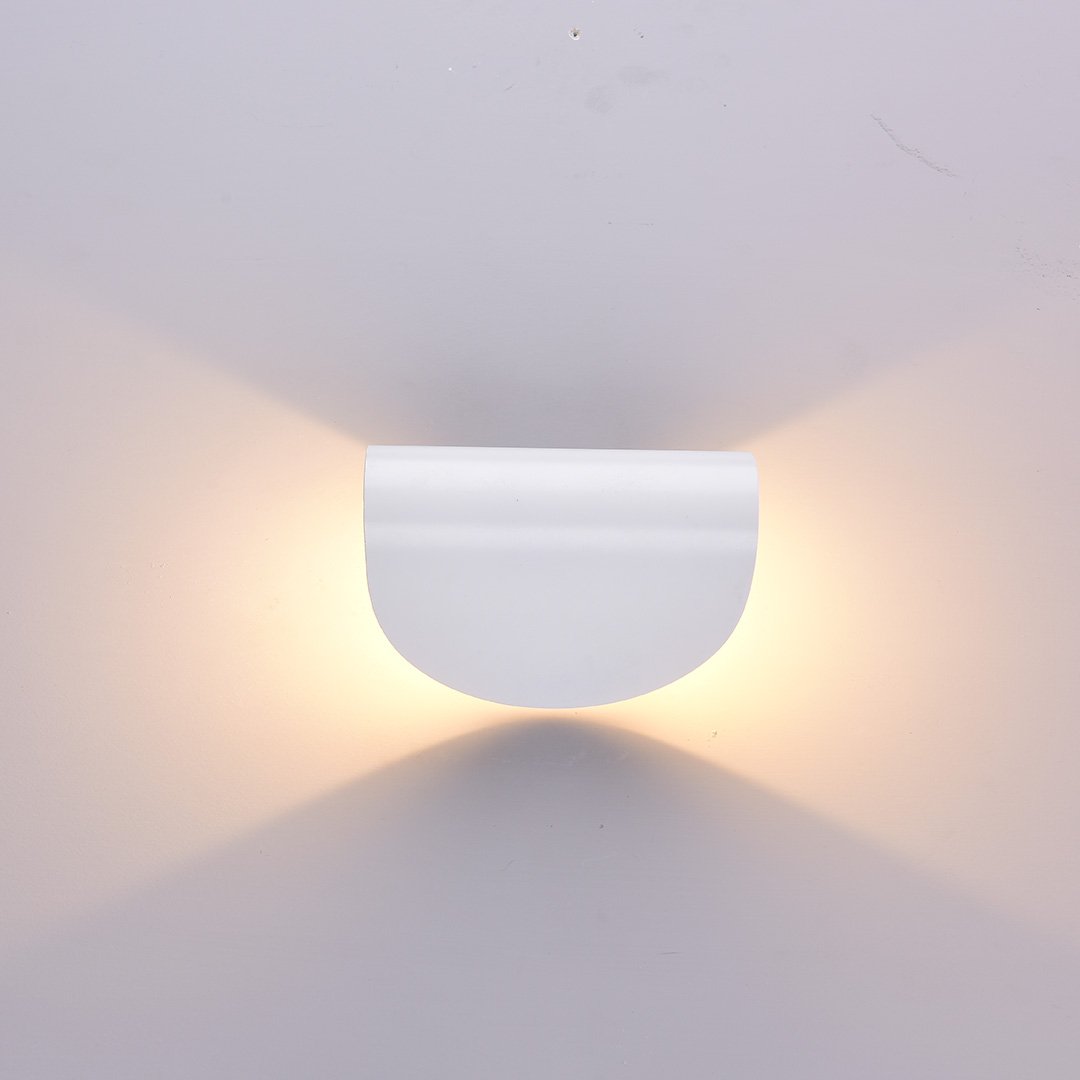 Modern white wall sconce with minimalist design, emitting warm ambient light. Ideal for contemporary home decor and interior lighting solutions.