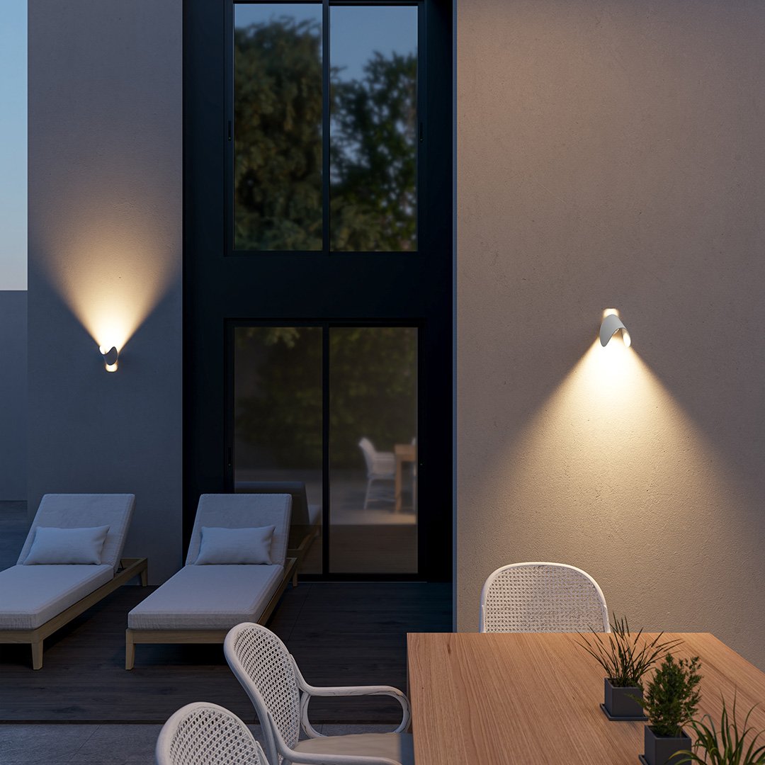 Modern outdoor patio with sleek wall lights, wooden table, and white chairs. Features minimalist design, lounge chairs, and evening ambiance.