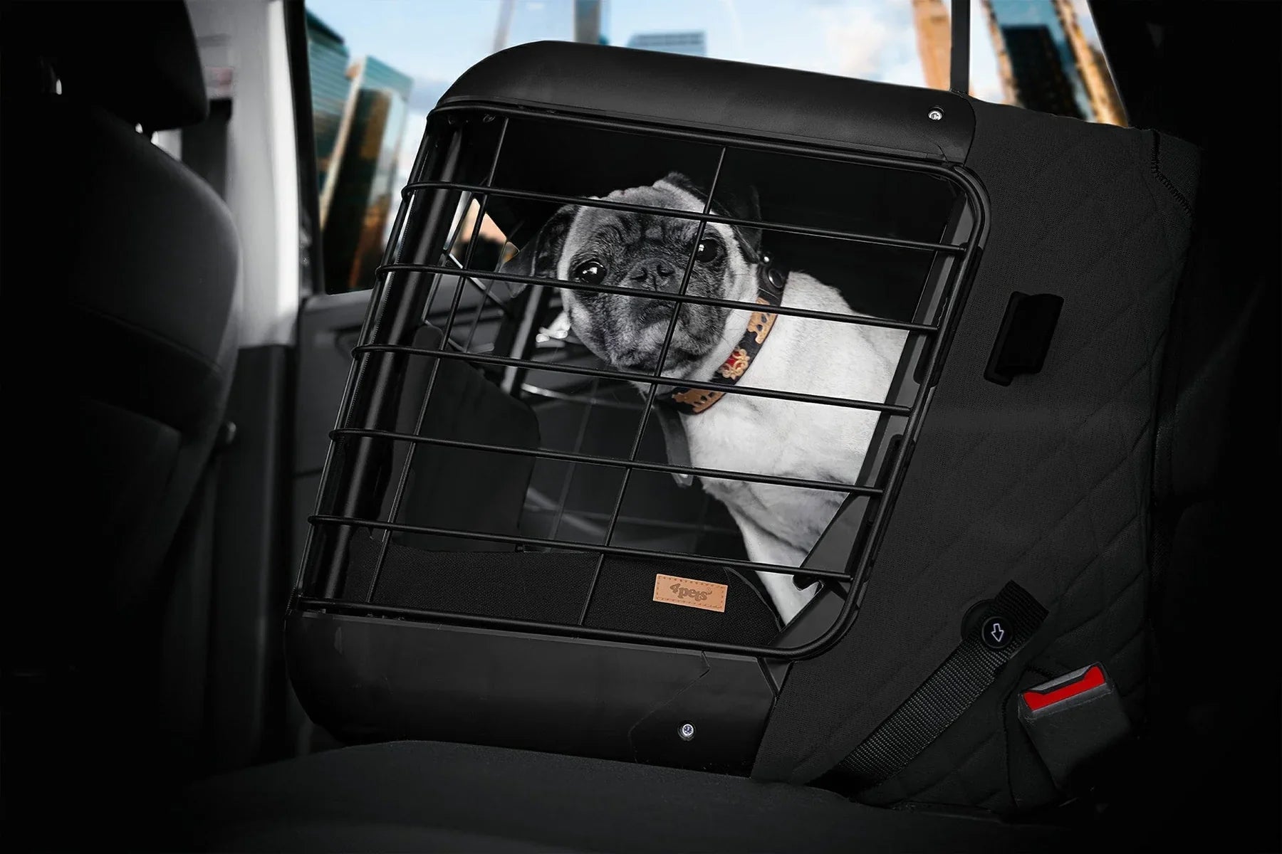 Pug in a black pet car seat carrier with safety bars, secured in a vehicle. Ideal for pet travel, dog safety, and comfortable transportation.