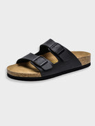 Black leather sandal with dual adjustable straps and cork footbed on a white background. Comfortable, stylish footwear for casual wear.