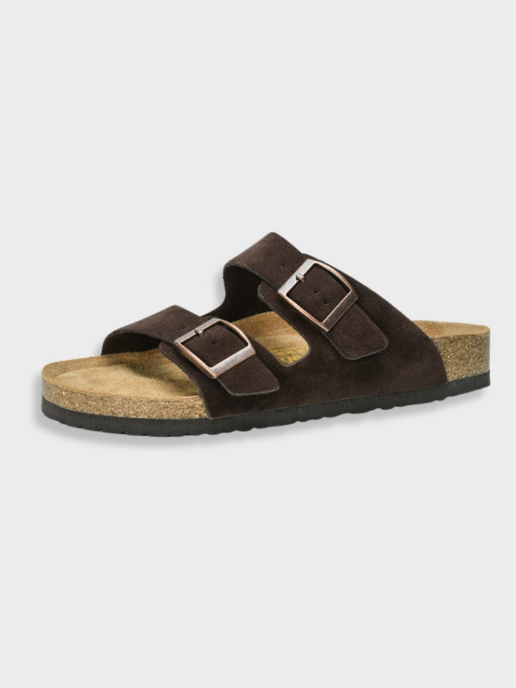 Dark brown suede sandals with dual adjustable straps and cork footbed, featuring a slip-on design. Perfect for casual summer wear and comfort.