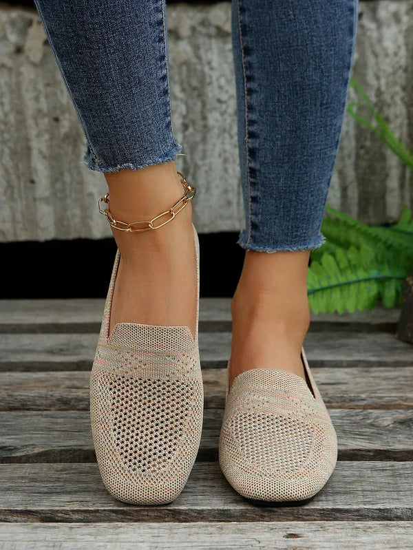 Women's beige woven loafers with a stylish chain anklet, paired with blue skinny jeans. Perfect casual footwear for summer fashion trends.