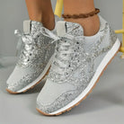 Silver glitter sneakers with mesh detailing and white soles, featuring lace-up closure. Stylish women's footwear for casual wear and fashion trends.