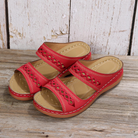 Red women's sandals with cutout design, double straps, and cushioned sole on wooden background. Stylish summer footwear, comfortable and trendy.