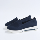 Navy blue slip-on sneakers with breathable mesh upper, cushioned white sole, and subtle heel design. Comfortable women's casual footwear.