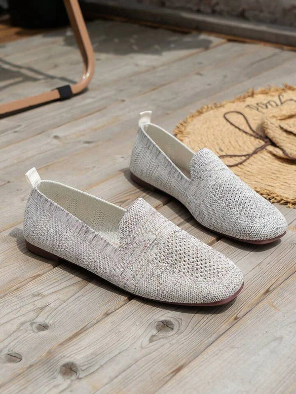 Casual gray woven slip-on loafers on wooden floor, featuring breathable fabric and flat soles, perfect for comfortable everyday wear.