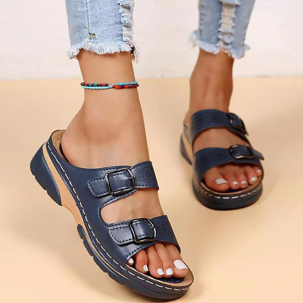 Women's navy blue orthopedic sandals with double buckle straps, worn with ripped jeans. Comfortable footwear for casual style and foot support.