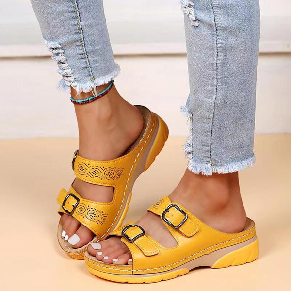 Yellow orthopedic sandals with double buckle straps worn by a person in distressed jeans. Comfortable footwear for women, ideal for casual wear.