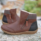 Brown leather ankle boots with side zippers, black heel accents, and textured cuffs, placed outdoors on a stone surface. Fashionable women's footwear.