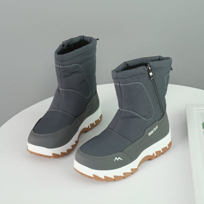 Gray winter boots with white soles and side zippers on a white surface. Durable, waterproof footwear ideal for cold weather and outdoor activities.