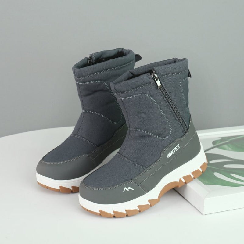 Gray winter boots with side zippers, thick white soles, and brown treads on a white surface. Ideal for cold weather, snow, and outdoor activities.