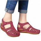 Women's red orthopedic sandals with adjustable straps, open-toe design, and cushioned sole, paired with rolled-up blue jeans. Comfortable summer footwear.