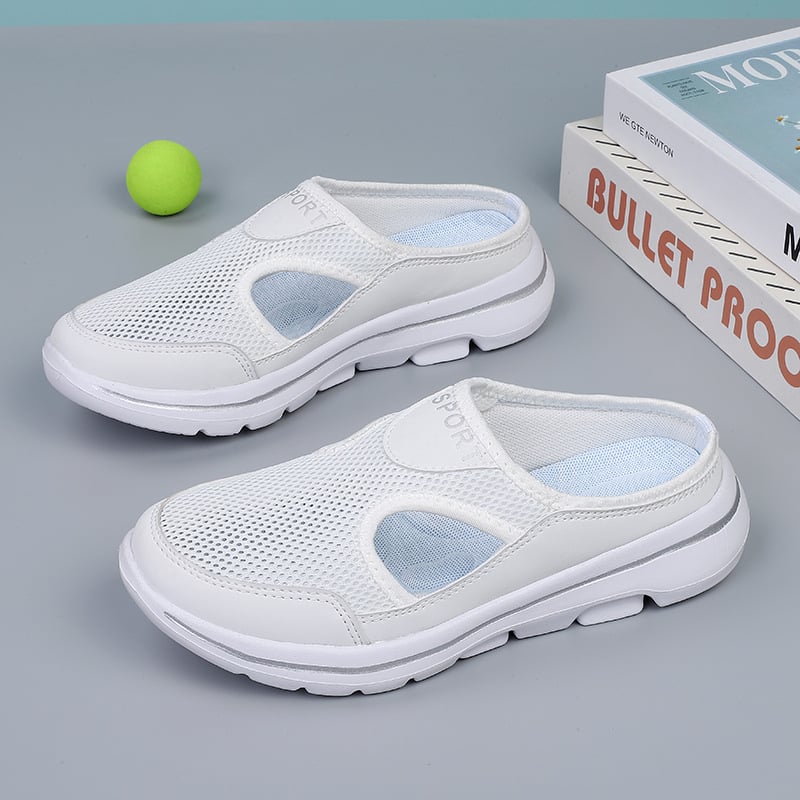 White mesh slip-on sneakers with cushioned soles on a gray surface, next to a green tennis ball and books. Comfortable, breathable footwear.