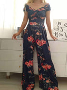 Floral navy blue jumpsuit with red and pink flowers, featuring an off-shoulder design and wide-leg pants, perfect for summer fashion trends.