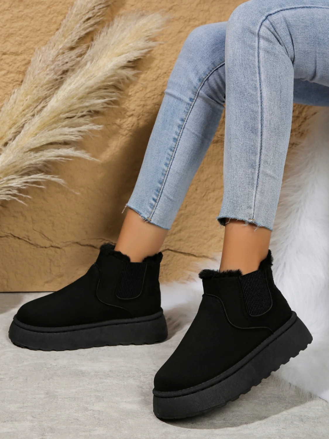 Black suede ankle boots with faux fur lining, worn with light blue skinny jeans. Stylish winter footwear, perfect for casual outfits and cold weather.