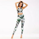 Woman wearing green floral sports set, featuring a sleeveless crop top and matching leggings. Perfect for yoga, gym, or activewear fashion.