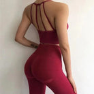 Woman in red athletic wear with decorative back straps, showcasing fitness fashion. Ideal for yoga, gym, or active lifestyle enthusiasts.