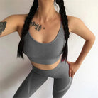 Gray sports bra and leggings set with decorative back stripes, worn by a woman with braided hair. Ideal for fitness, yoga, and activewear fashion.