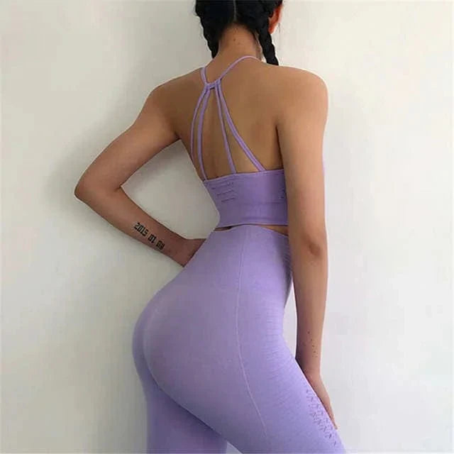 Woman in purple sports set with decorative back stripes, braided hair, and tattoo, showcasing fitness fashion. Ideal for activewear and workout style.